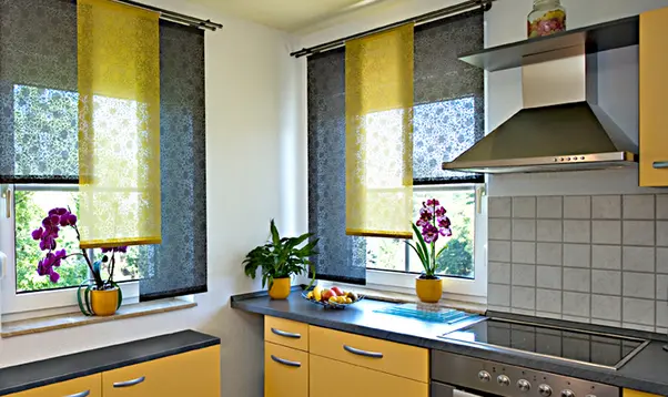 Gelbe und schwarze Stoffbahnen mit Muster als Fensterdekoration in einer gelb eingerichteten Küche