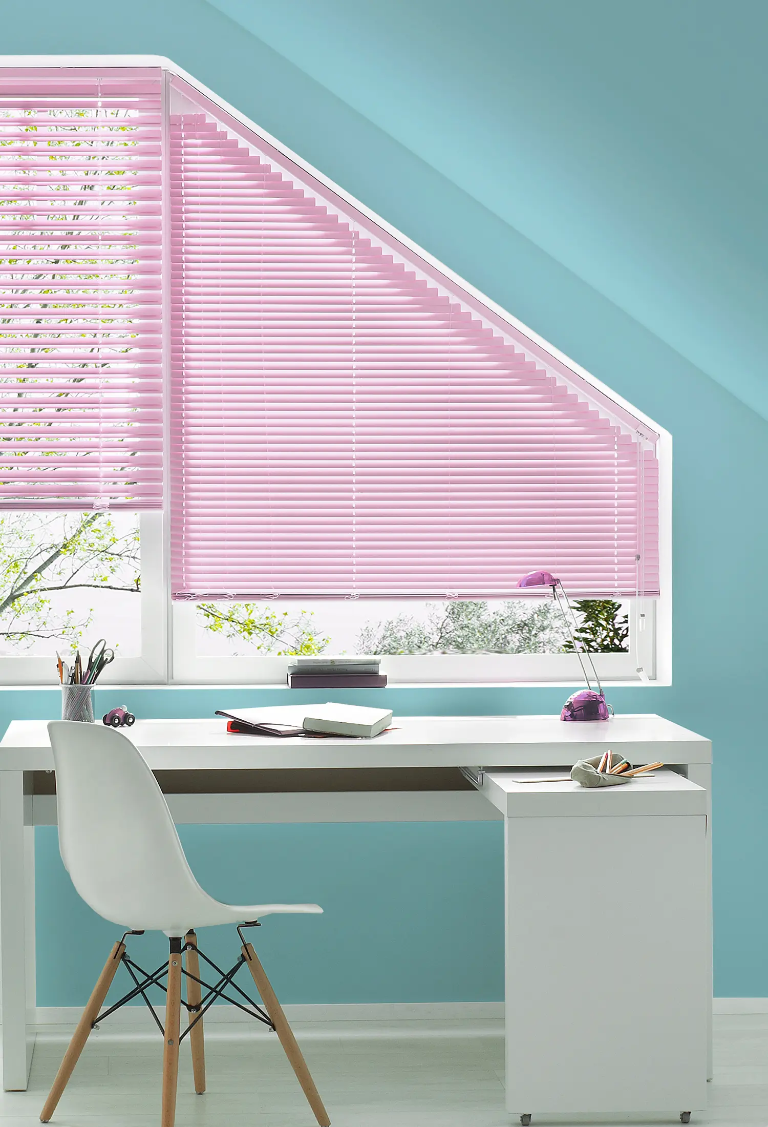 Heller Bereich mit schräger Decke, einem weissen Tisch und rosafarbenem Sichtschutz am Fenster.