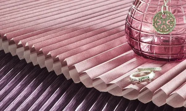 Detailansicht eines violetten Wabenstoffs mit Schmuckstücken und Glasdeko