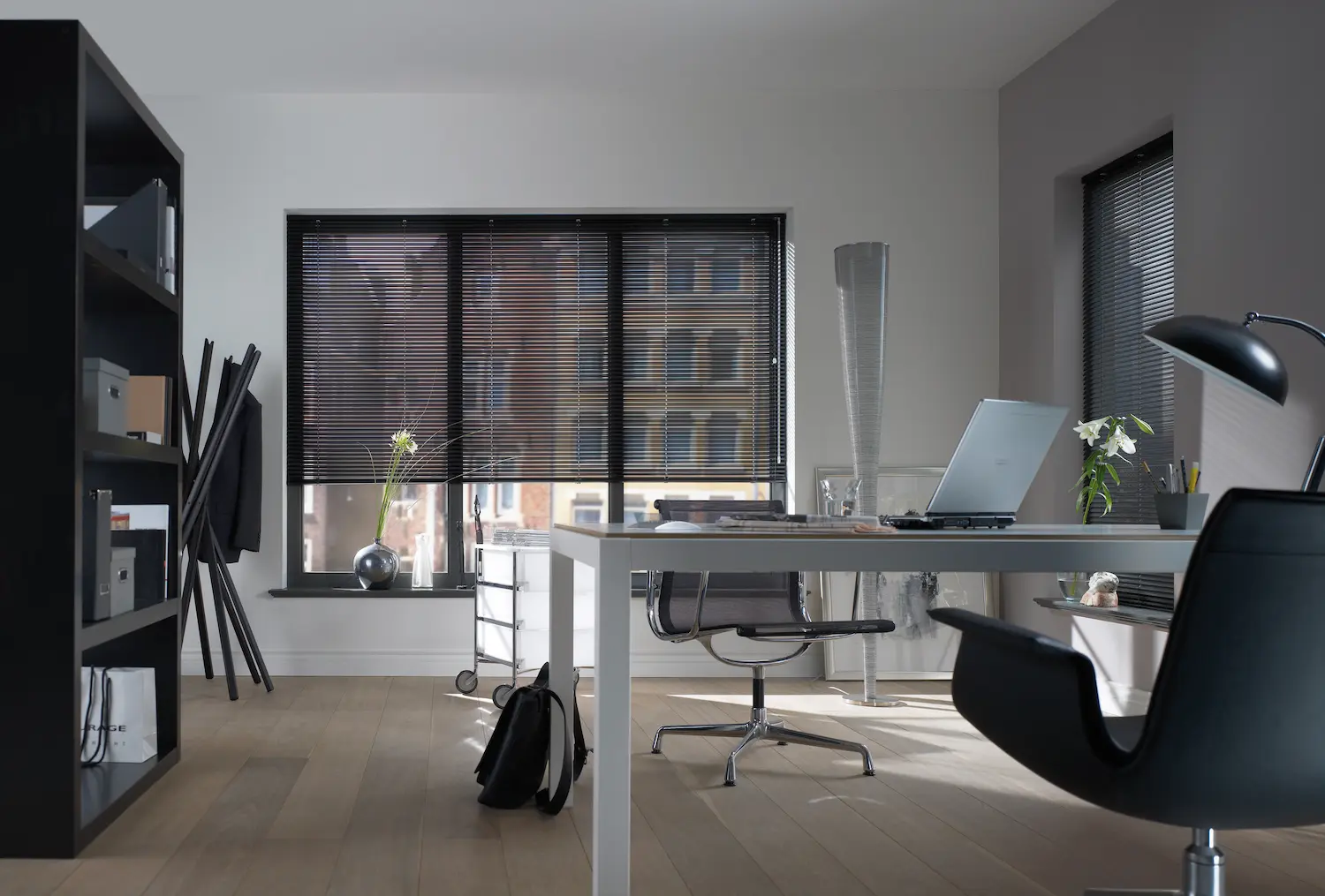 Modernes Büro mit schwarzen Jalousien an den Fenstern und stilvoller Einrichtung.