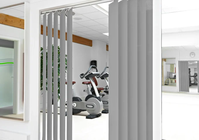 Graue vertikale Vorhänge in einem Fitnessraum als flexible Raumtrennung