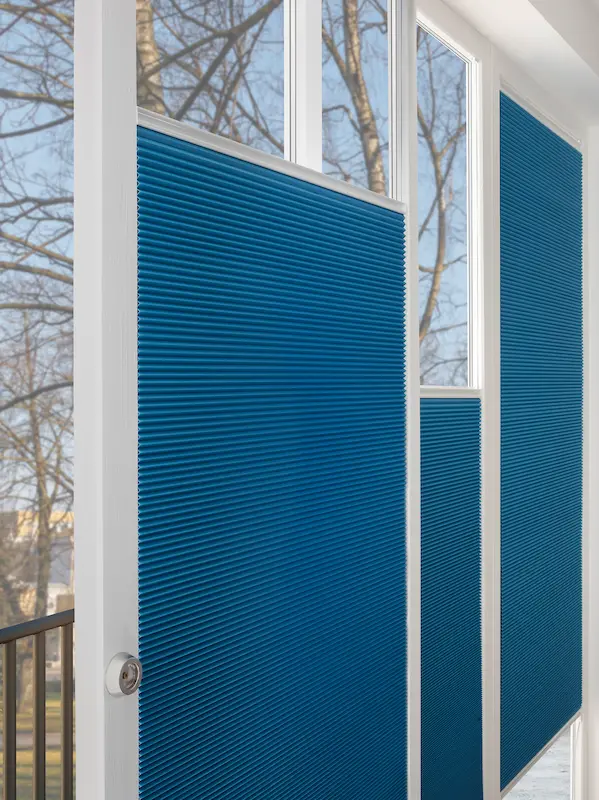 Tür und Fenster mit blickdichtem blauen Wabenplissee zur Lichtregulierung in einem hellen Raum