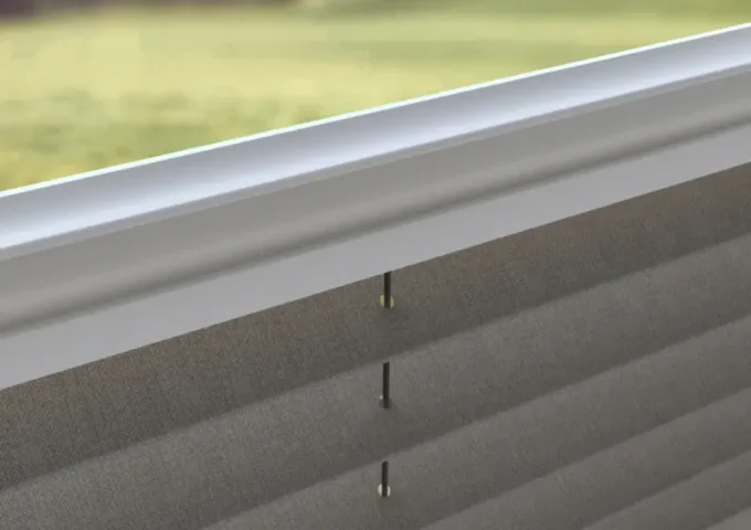 Nahaufnahme eines plissierten Behanges mit seitlich geführter Schnur in einer dezenten Fensterschiene